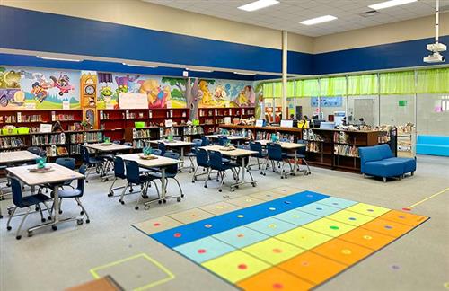 A view of the colorful library with books on shelves, and desks neatly aligned