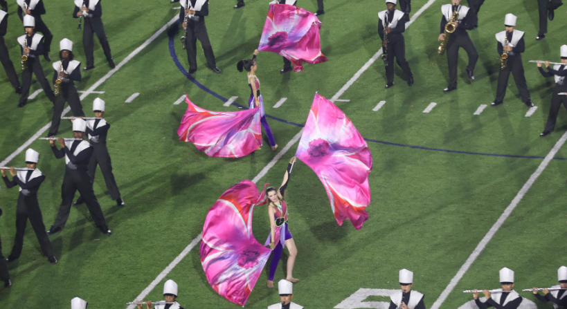 Two Color Guard students performing with Marching Band