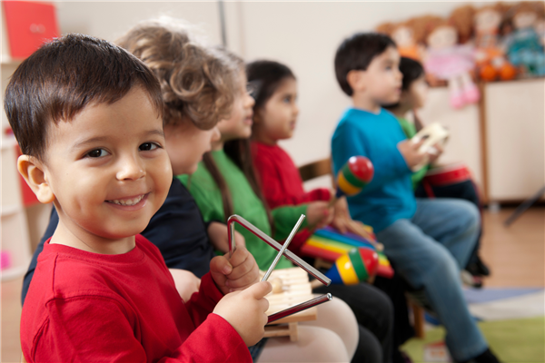 Toddler and young children playing instrumentos on the background, and one child smiling 
