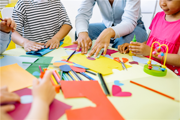 Teacher and Toddlers Hands Gluing Pieces of Colorful Paper